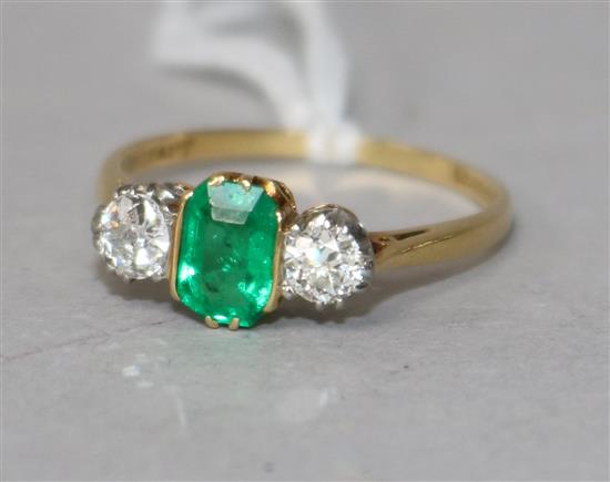 An 18ct gold, emerald and diamond three stone ring, size O.